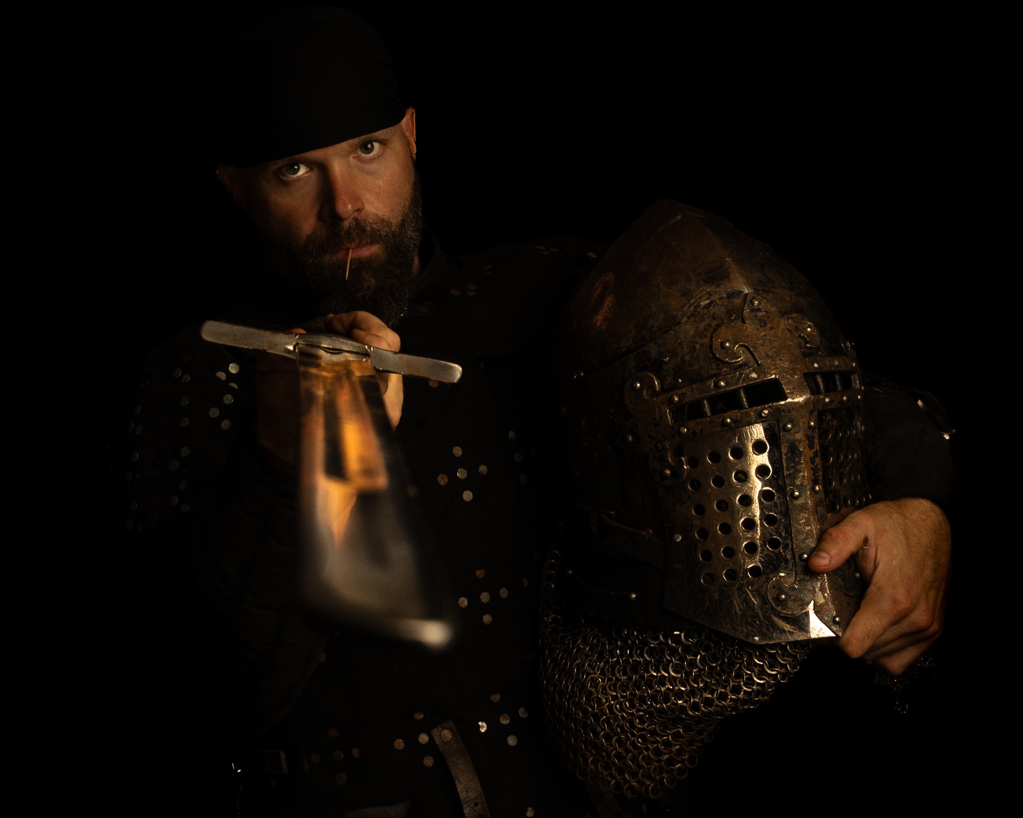 Cole "Tooth Pick" Waldron in armor, holding a sword and a great helm, toothpick in his teeth